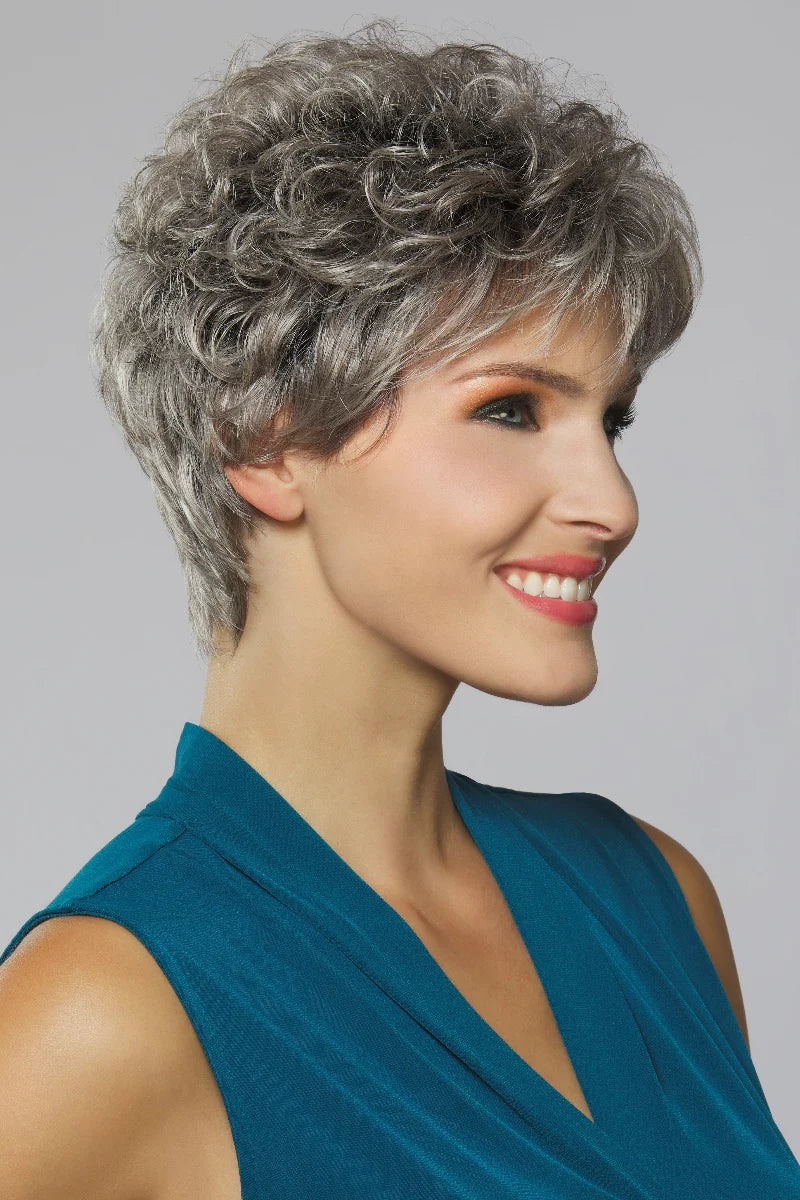 Woman with styled gray hair wearing a blue top against a gray background