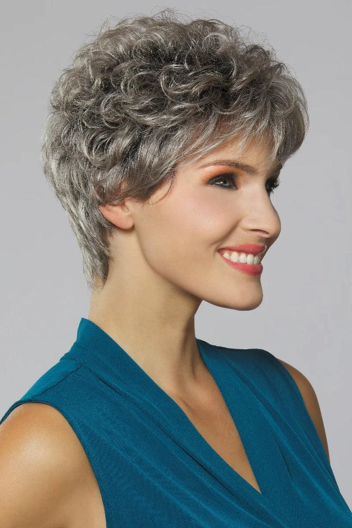 Woman with styled gray hair wearing a blue top against a gray background