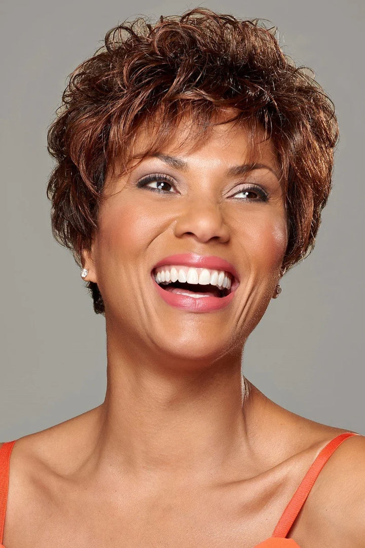 Woman with short, styled hair smiling against a gray background