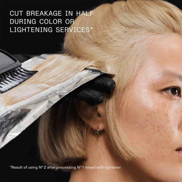 Person with blonde hair undergoing hair color or lightening service with text on cut breakage.