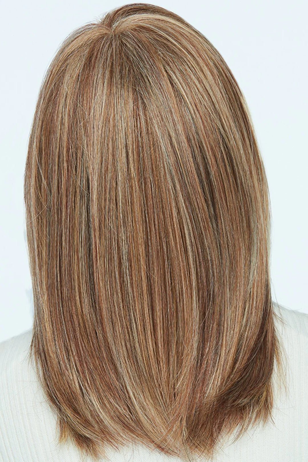 Blonde hair with brown roots styled in a straight cut on a white background