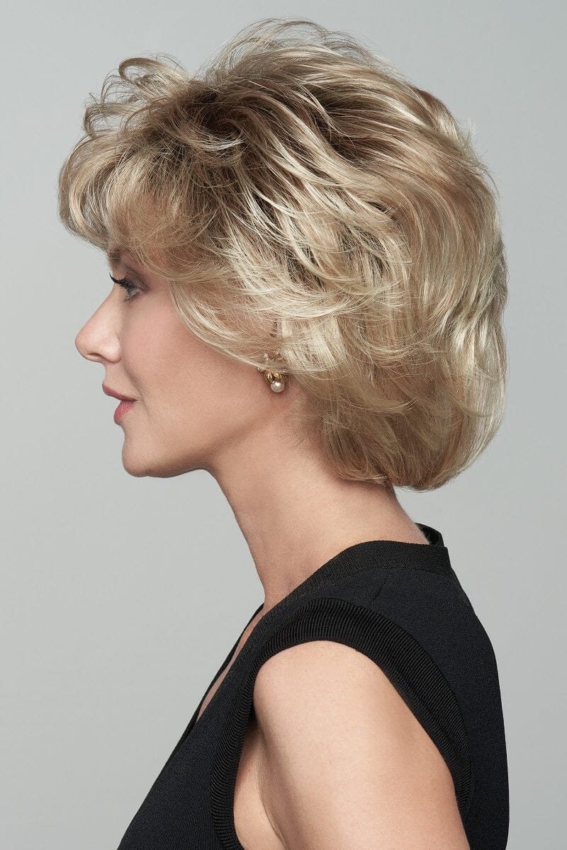 Woman with styled blonde hair in a side profile against a gray background