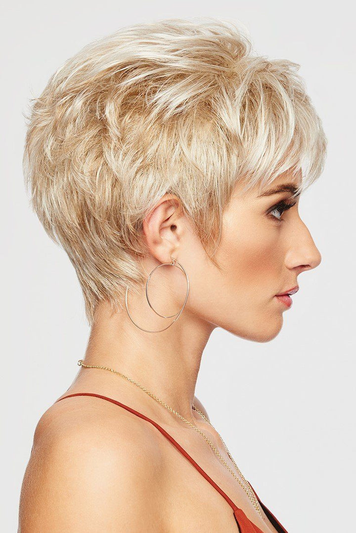 Side profile of a woman with short blonde hair wearing hoop earrings against a light background