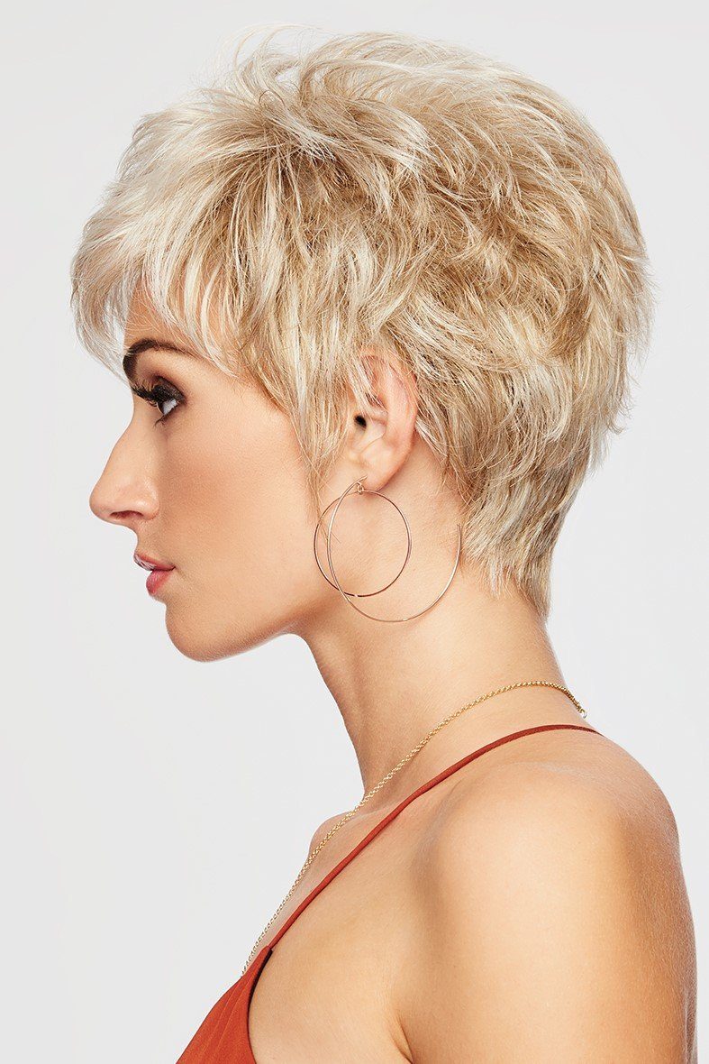 Woman with short blonde hair and hoop earrings on a light gray background