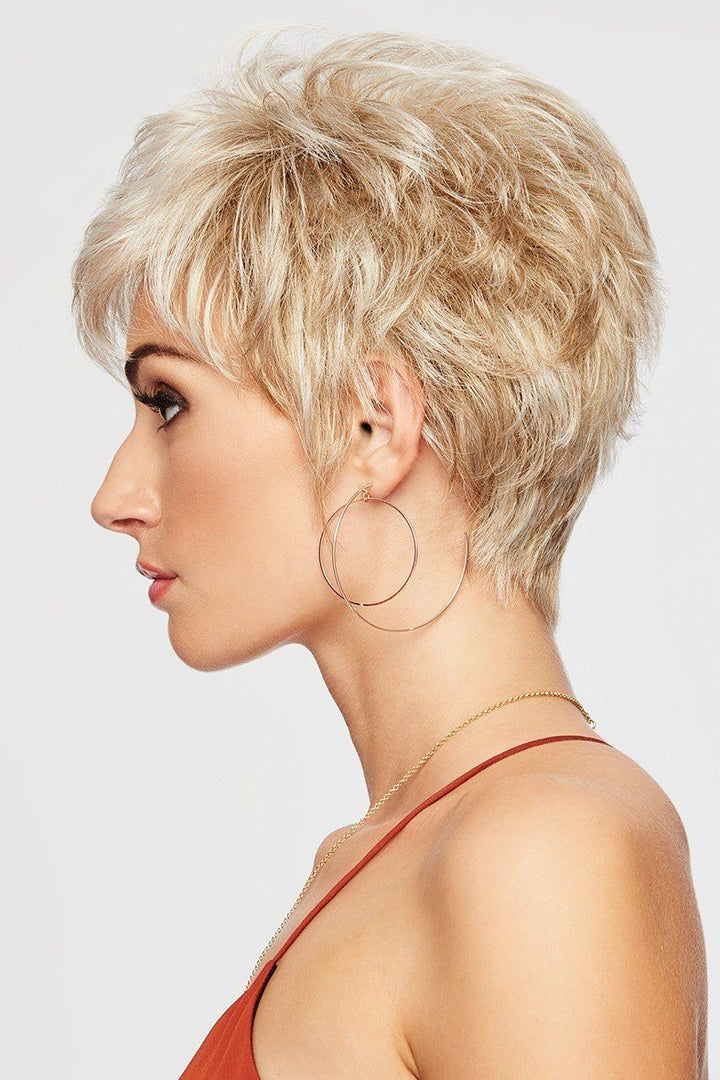 Woman with short blonde hair and hoop earrings on a light gray background