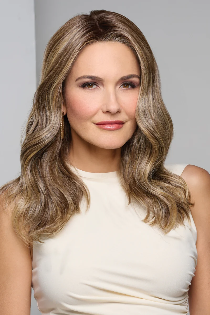 Woman with wavy hair wearing a white top against a gray background