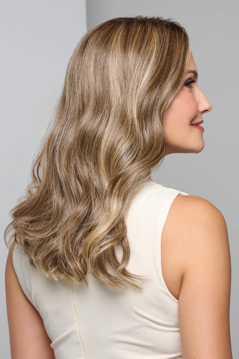 Woman with long, wavy blonde hair wearing a white sleeveless top against a gray background