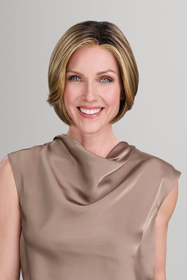 Woman wearing a beige sleeveless top against a plain background