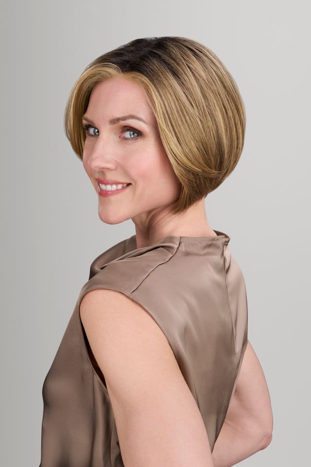 Woman with a short, styled haircut wearing a brown top against a gray background