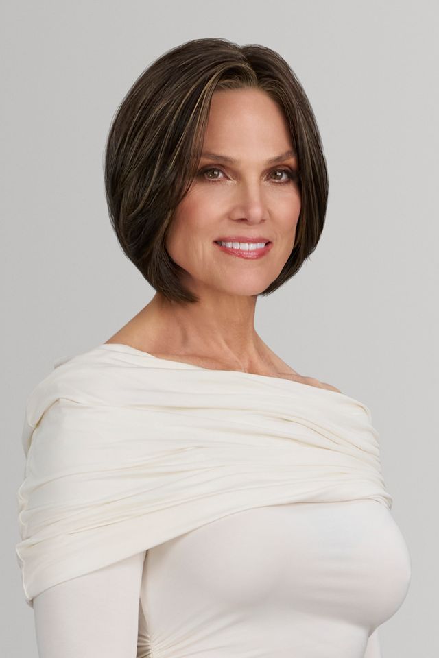 Woman with a short haircut wearing a white off-shoulder dress against a gray background