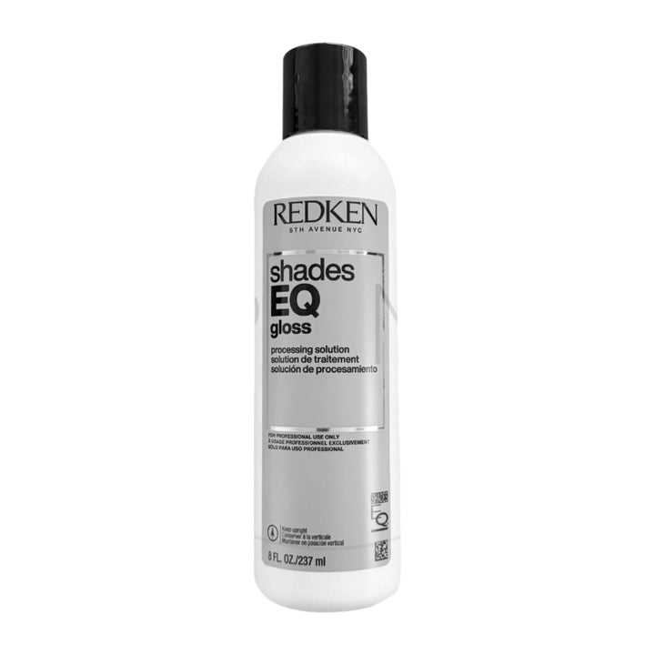 Redken Shades EQ gloss bottle on a marble background